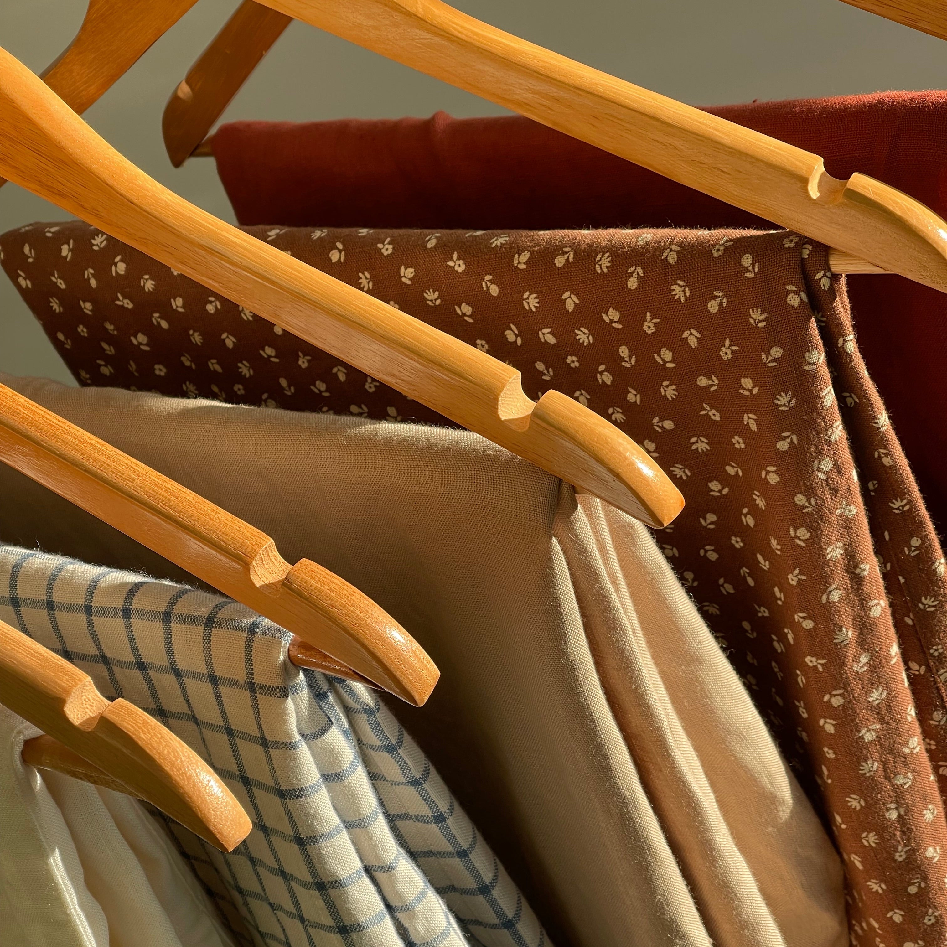 Linen garments in solid, floral and checked fabrics hanging in natural light