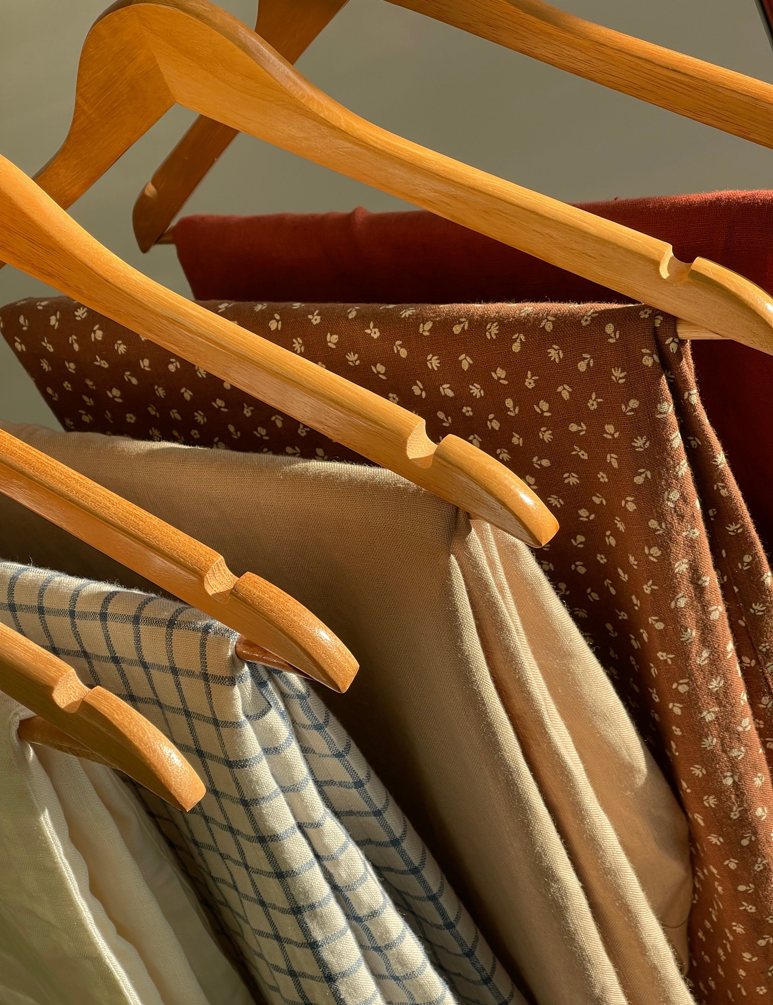 Linen garments in solid, floral and checked fabrics hanging in natural light