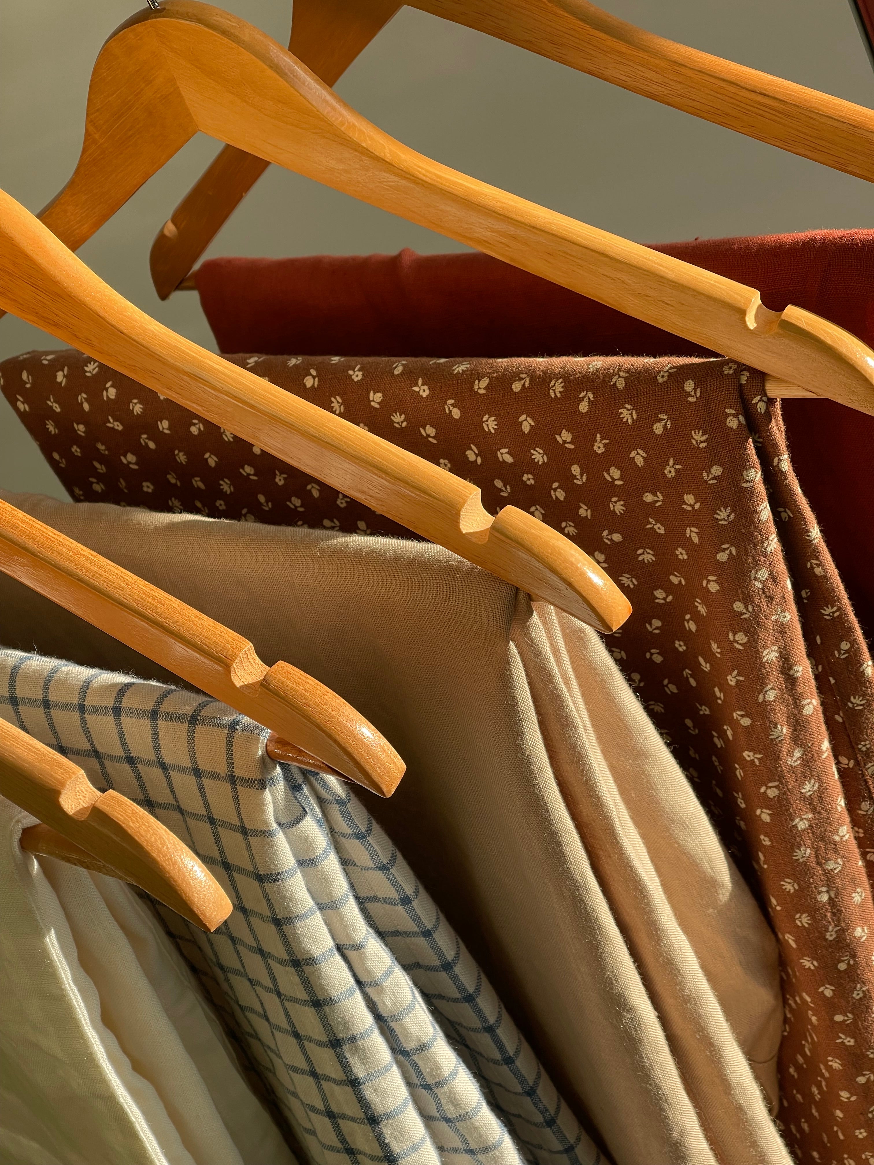 Linen garments in solid, floral and checked fabrics hanging in natural light